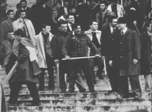 Immagine in bianco e nero che ritrae i mazzieri neo-fascisti sulla scalinata della Facoltà di Giurisprudenza durante l'assalto del1968. In primo piano è riconoscibile la figura di Giorgio Almirante.